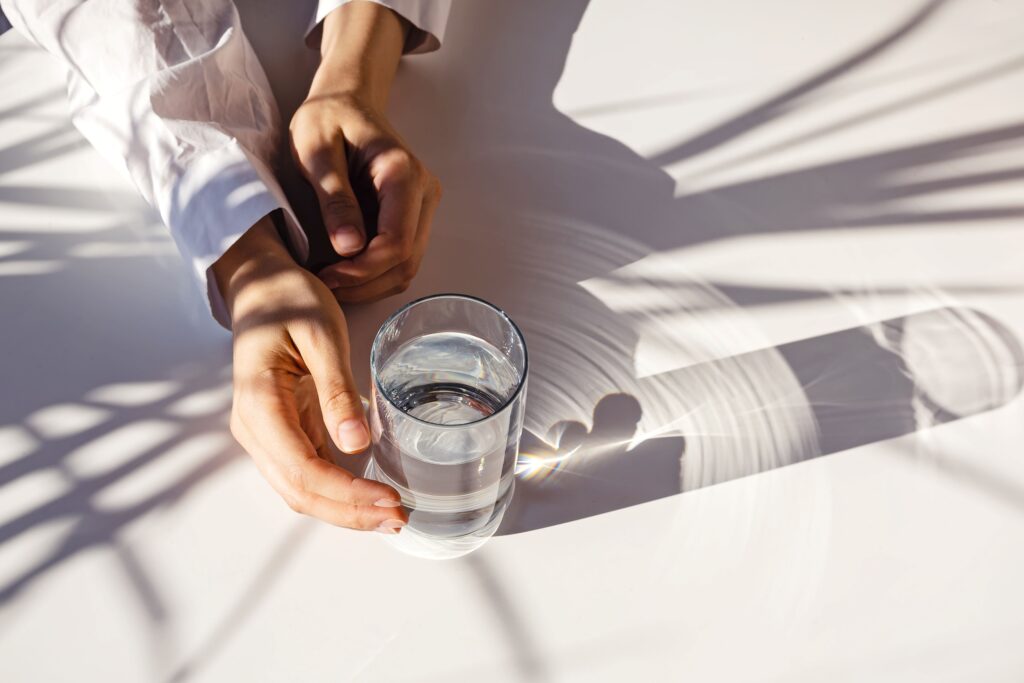 Glas mit klarem Wasser auf hellem Tisch symbolisiert Reinheit und Gesundheit